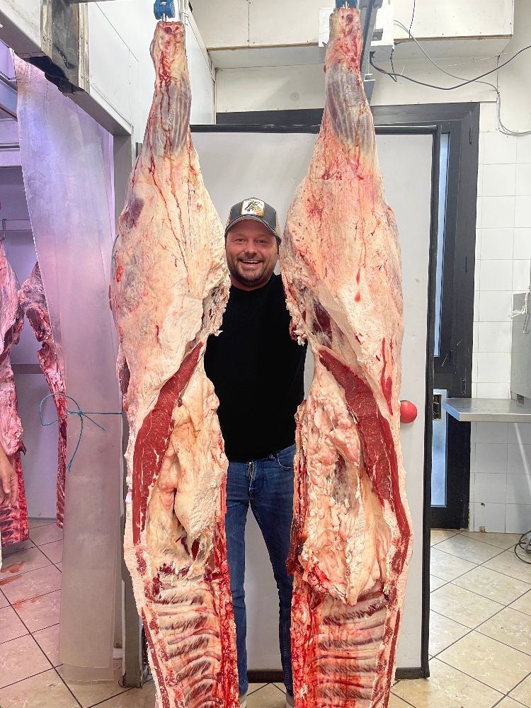 Leonhard Bader zwischen zwei Chianina-Rinderhälften im Schlachthof